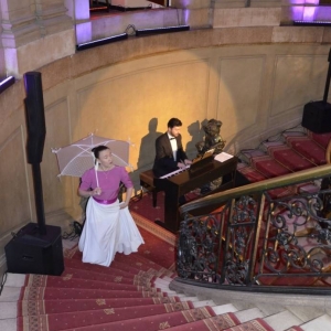Zdjęcie przedstawia artystów występujących u szczytu schodów wewnątrz Pałacu Kawalera, podczas koncertu pt. Jak bal to bal