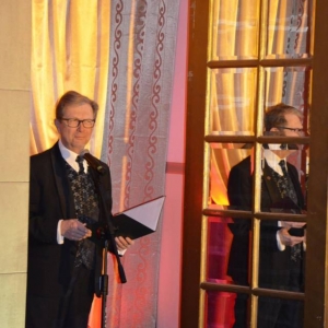 Zdjęcie przedstawia konferansjera w roli którego wystapił Pan Jacek Woleński w witrynie okiennej znajdującej się u szczytu schodów wewnątrz Pałacu Kawalera, zapowiadającego kolejne etapy koncertu pt. Jak bal to bal
