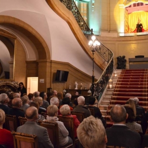 Zdjęcie przedstawia konferansjera koncertu  występującego w witrynie okiennej znajdującej się u szczytu schodów wewnątrz Pałacu Kawalera oraz publiczność  podczas koncertu pt. Jak bal to bal