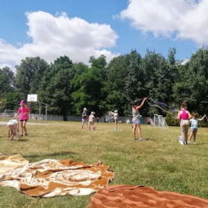 Zdjęcie przedstawia uczestników półkolonii podczas wspólnej zabawy na boisku sportowym w Nakle Śl.