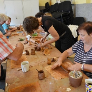 Zdjęcie przedstawia uczestników warsztatów ceramicznych podczas wykonywania swoich prac