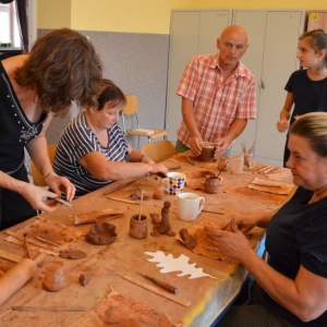 Zdjęcie przedstawia uczestników warsztatów ceramicznych podczas wykonywania swoich prac