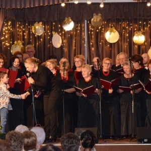 Zdjęcie przedstawia dyrygent chóru Ewę Zug oraz chór Jutrzenka podczas noworocznego koncertu kolędowego