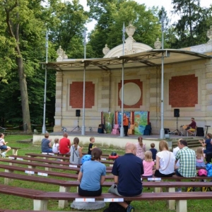 Zdjęcie przedstawia publiczność oraz amfiteatr w świerklanieckim parku w trakcie przedstawienia teatralnego