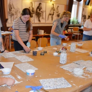 Zdjęcie przedstawia uczestników warsztatów wakacyjnych z mozaiki witrażowej podczas tworzenia mozaiki szklanej
