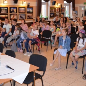 Zdjęcie przedstawia publiczność oraz uczestników konkursu wokalnego
