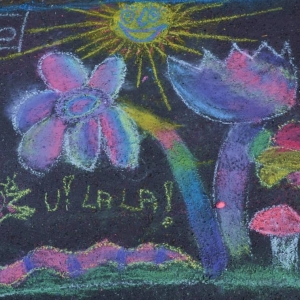 Zdjęcie przedstawia rysunki konkursowe wykonane kredą na alejce parkowej